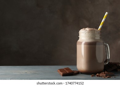 Glass of chocolate milkshake on wooden table. Summer drink