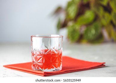 Glass Of Chocolate Red Orange Negroni, An Italian Cocktail, An Aperitif, First Mixed In Firenze, Italy, In 1919, Alcoholic Bitter Cocktail Served On The Light Gray Table.