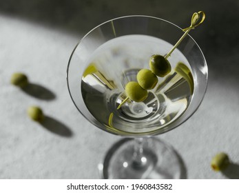 Glass of classic dry martini cocktail with olives on grey stone background. With free space for your text