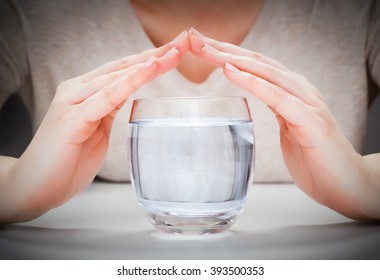 A Glass Of Clean Mineral Water Covered By Woman's Hands. Concept Of Environment Protection, Healthy Drink.