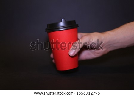 Glass for coffee and cappuccino red color of holds guy, on the black backdrop of.