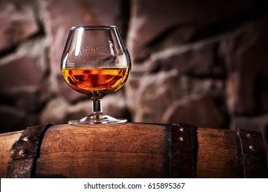 Glass Of Cognac On The Old Wooden Barrel