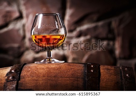 Glass of cognac on the old wooden barrel