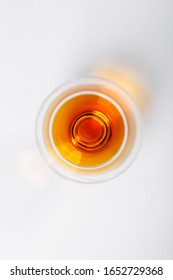 A glass of cognac stands on a white background. The view from the top.