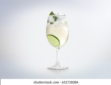 Glass Of A Cold Cocktail Drink With White Wine / Vermouth, Slice Of Lemon / Lime And A Mint Leaf. Isolated On White Background. 