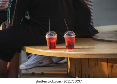 Glass Of Cold Coctail In A Plastic Cup On A Wooden Table Outside