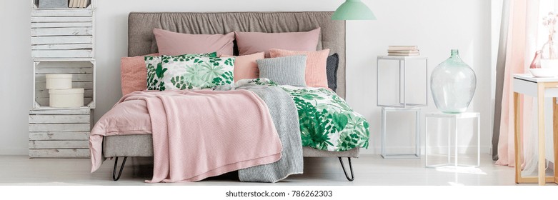 Glass Containers On White Stools Next To King-size Bed With Pink Blanket In Pastel Cozy Bedroom Interior