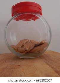 Glass Cookie Jar With Red Plastic Lid And Broken Cookies In Bottom Of Jar.