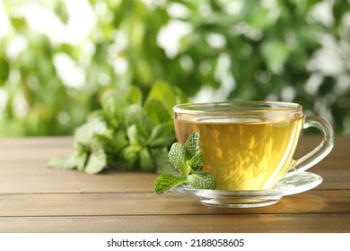 Glass cup of aromatic green tea with fresh mint on wooden table against blurred background. Space for text - Powered by Shutterstock