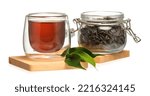 Glass cup of black tea and jar with dry leaves on white background