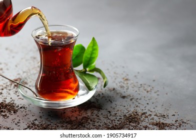 Glass Cup Of Black Tea Pouring From Teapot With Fresh Tea Leaves, Traditional Turkish Brewed Hot Drink