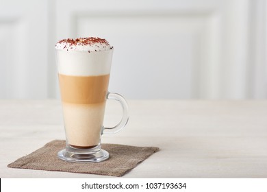 Copa de vidrio de café con leche sobre mesa de madera