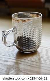 Glass Cup Of Coffee With Leftover Coffee Grounds On A Wooden Table, Side View