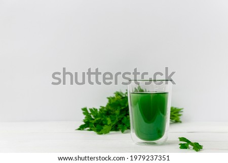 Glass cup with healthy drink of liquid chlorophyll on white background with green leaves. Image with copy space