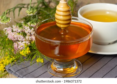 A glass cup with honey on a background of wildflowers. Honey with herbs. Health and benefits
