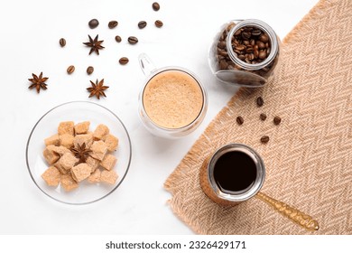 Glass cup of hot espresso and jar with coffee beans on white background