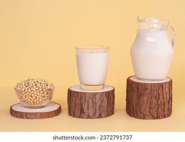 Glass cup and jug with organic soy drink and bowl full of soy beans on wooden podium on beige background. vegan product, Minimalist concept and Healthy drinks - Powered by Shutterstock