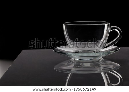 Glass cup standing on table isolated on black background, close up