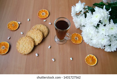 glass cup with tea, cookies, candy and white chrysanthemum flowers on a wooden table, closeup - Shutterstock ID 1431727562
