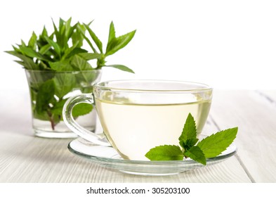 Glass cup of tea with mint on the white wooden table