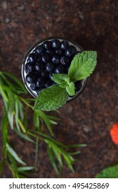 Glass Cup Of Yogurt With Fresh Blueberry And Green Mint Leaf On Marble Kitchen Counter. Overhead View. Food Background.