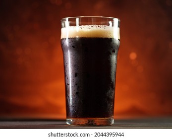 A Glass Of Dark Beer In The Center, Orange Backlight. Porter, Stout Or Brown Ale