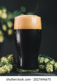 A Glass Of Dark Beer, Craft Stout Or Porter With Green Hop Cones