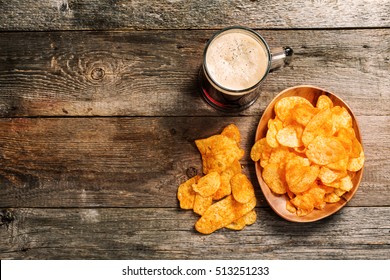 Glass Of Dark Beer With Potato Chips On A Wooden Background. Top View