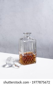 Glass decanter with whiskey on a white table and gray wall