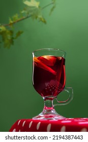 Glass With Delicious Aromatic Cocktail, Mulled Wine With Orange Slice And Cinnamon Stick Isolated Over Green Background. Concept Of Taste, Drink, Healthy Ingredients, Seasonal Drink. Copy Space For