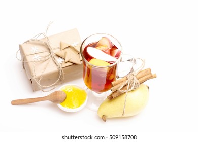 Glass Of Delicious Glintwein Or Mulled Hot Wine, Gift Wrapped In Craft Paper With Bow, Snowflakes And Cinnamon, Honey, Pear Isolated On White Background