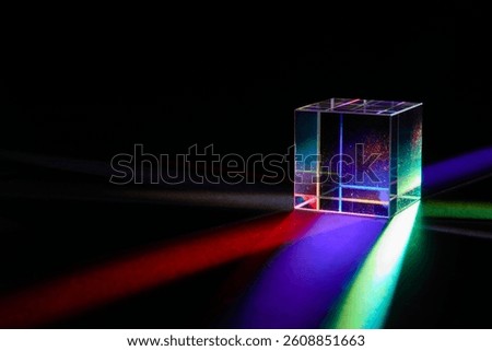 A glass dichroic prism disperse light into different colors on a black background