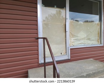 A Glass Door Next To A Glass Widow That Has Paper Pinned To The Back Of Them So People Can't See Inside.