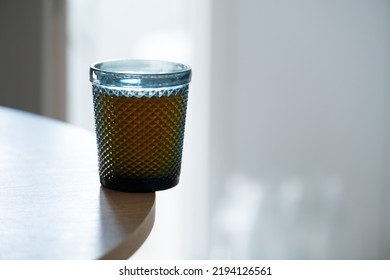 A Glass With A Drink Is On The Edge Of The Kitchen Table