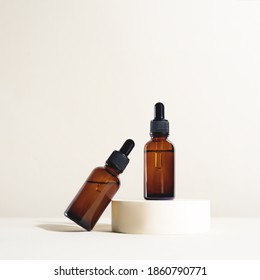 Glass dropper bottles with a pippette with black rubber tip on the podium and bright background. Nature Skin concept. Organic Spa Cosmetics. Trendy concept.