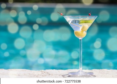 Glass of dry martini cocktail on the pool nosing at the tropical resort. Horizontal. Bokeh details