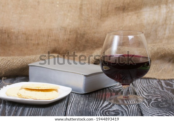 A
glass of dry red wine and broken unleavened bread lie on a plate.
To celebrate the Lord's Supper. Nearby lies the
Bible.