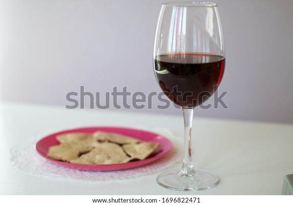 A glass of dry red wine and\
unleavened bread on a plate. Celebration of the Lord\'s\
Supper.