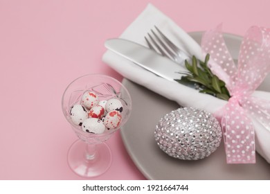 Glass with Easter eggs on the background of plates and cutlery. Variative focus