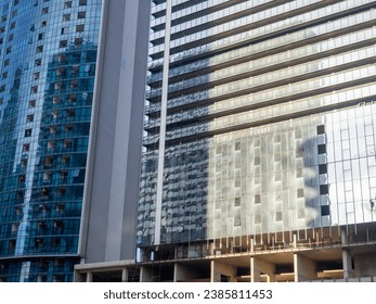 Glass facade of a house under construction with open windows. Construction safety net. Geometry in architecture. Architecture background.