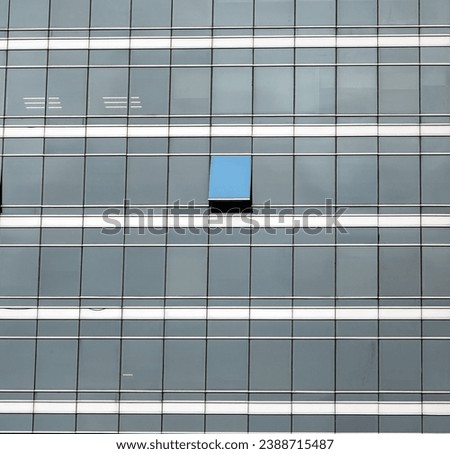 The glass facade of skyscraper with  one window is open 