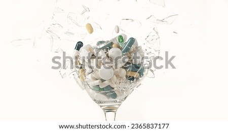 Glass filled with Capsules Exploding against White Background