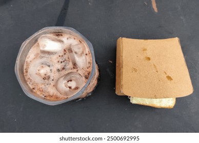 A glass filled with a chocolate-flavored icy beverage, possibly a milkshake or smoothie, with visible layers of chocolate syrup and topped with ice cubes. - Powered by Shutterstock