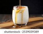 a glass filled with homemade yogurt and drizzled with natural honey