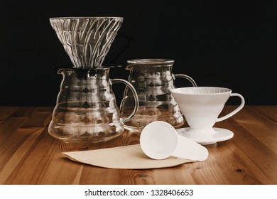 Glass flask, paper filters, glass and ceramic dripper, spoon for pour-over coffee. Alternative coffee brewing method. Stylish accessories and items for alternative coffee on wooden table - Shutterstock ID 1328406653