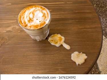 A Glass Of Flat-white Coffee Stands On The Table And Next To The Visible Spilt Milk, The View From Above