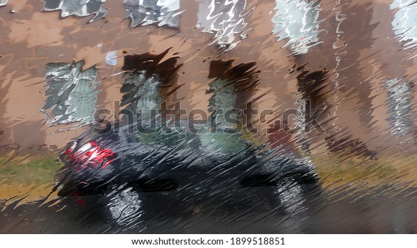 Glass flooded with water from rain. Heavy\
rain shower. In the background there is a car and a building.\
Dangerous driving, bad weather, slippery\
road.