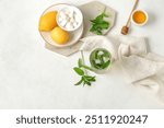 Glass of fresh icy mint tea with lemons, honey and sugar cubes on white background