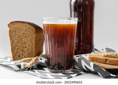 Glass of fresh kvass and bread on light background