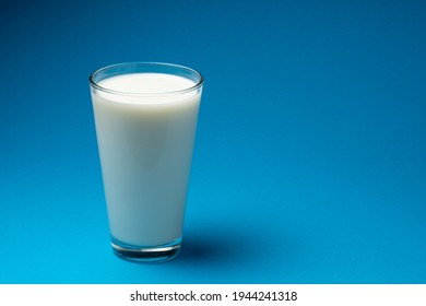 Glass of fresh milk isolated on blue background. 